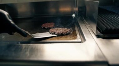 Profesyonel restoran mutfağı yakın çekim şefi spatula parçacıklı burgerli lezzetli köfteler yapıyor.