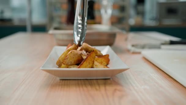Profesjonalny Kucharz Wyjmuje Pieczone Ziemniaki Przyprawami Szczypcami Kładzie Talerzu — Wideo stockowe
