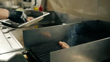 Otel restoranında profesyonel mutfak, şef ızgarada tavuk filetosu hazırlar ve serer.