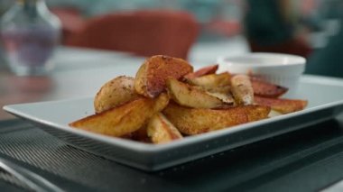 Restoran yemeği ekşi krema sosu ve masada baharatlı fırında patates dilimleri.