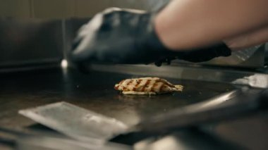 Otel restoranındaki profesyonel mutfakta şef fırında pişirmek için domuz pastırması ve tavuk filetosu hazırlar.