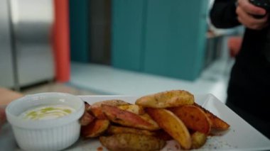 Restoran yemeği ekşi krema sosu ve masada baharatlı fırında patates dilimleri.