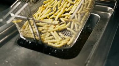 Otelin restoranındaki profesyonel mutfak. Şef kızartmaları kızartma makinesinden çıkarıyor.