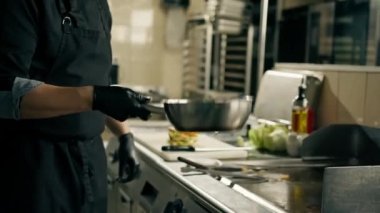 Otel restoranının profesyonel mutfağında şef lezzetli patates kızartmalarını kaseye atıyor.