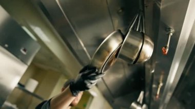 Otel restoranında profesyonel bir mutfak, şef kızartma tavasını çıkarır ve pişirmeden önce fırına koyar.