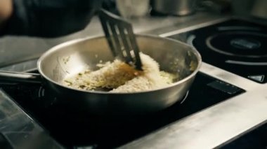 Otel restoranında profesyonel mutfak. Şef öğle yemeği için risotto hazırlıyor. Yakın plan pirinç karıştırıyor.