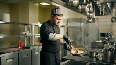 Otel restoranındaki profesyonel mutfak. Şef öğle yemeği için risotto hazırlıyor. Pirinç karıştırıyor.