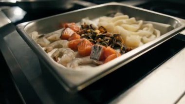 Otel restoranında profesyonel mutfak. Yakın plan deniz ürünleri osuruğu karides, midye ve somon balığı pişiriyor.