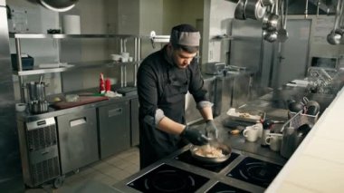 Otel restoranında profesyonel mutfak, şef karides, midye, somon balığı ve deniz ürünleri pişiriyor.