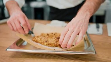 Profesyonel bir mutfakta spatula kullanarak aşçı pişirmek kızarmış tavuk filetosunu ekmek kırıntılarına koyar.