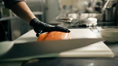 Otel restoranındaki profesyonel mutfak şefi büyük taze bir somon leşini bıçakla keser.
