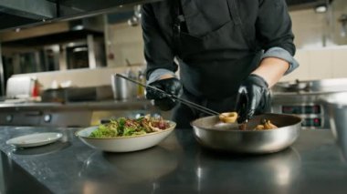 Otel restoranında profesyonel mutfak. Şef tabakta deniz ürünleri salatası için malzemeler hazırlıyor.