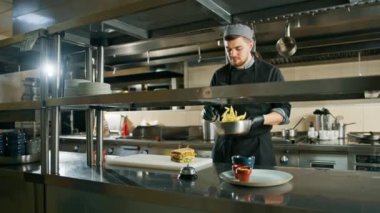 Otel şefinin restoranındaki profesyonel mutfak kulüp sandviçi patates kızartması sunumu yapıyor.