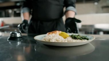 Otel restoranındaki profesyonel mutfak şefi ıspanaklı ve risottolu ızgara somon servis ediyor.