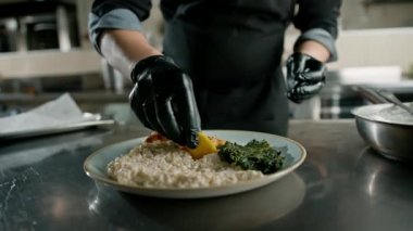 Otel restoranındaki profesyonel mutfak şefi ıspanaklı ve risottolu ızgara somon servis ediyor.