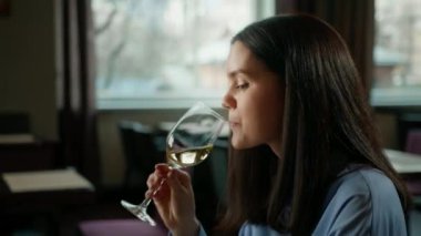 Bir otel restoranında bir adam ve bir kadın gülümseyen bir kızın yüzünde beyaz şarap içerler.