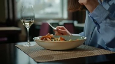 Bir otel restoranında, bir misafirin yakın planında bir bardak beyaz şarapla buluşup lezzetli bir deniz ürünleri salatasının tadını çıkarmak.