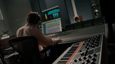 Stüdyo kayıt stüdyosunda çalışan enerji dolu ses mühendisi yapımcısı konsol ve hit yazılımları karıştırıyor.