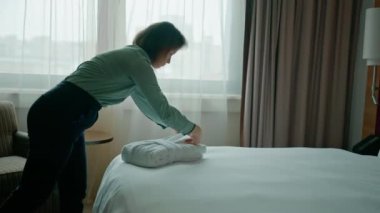 Üniformalı bir hizmetçi, misafir temizlik ve seyahat konsepti için lüks bir otel odası hazırlıyor.