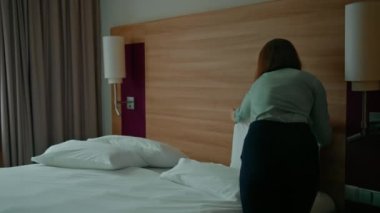 Üniformalı bir hizmetçi, misafir temizlik ve seyahat konsepti için lüks bir otel odası hazırlıyor.