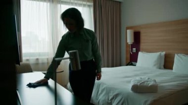 Oda temizliği ve seyahat konsepti için lüks otel odalarını hazırlarken üniformalı hizmetçi tozunu alıyor.