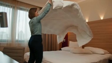 Üniformalı bir hizmetçi, misafir temizlik ve seyahat konsepti için lüks bir otel odası hazırlıyor.