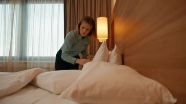 Üniformalı bir hizmetçi, misafir temizlik ve seyahat konsepti için lüks bir otel odası hazırlıyor.