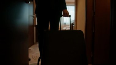 Bavullu bir adam uçuştan sonra bir otel odasına girer.