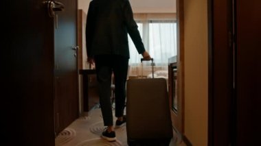 Bavullu bir adam uçuştan sonra bir otel odasına girer.