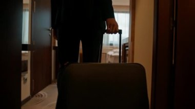 Bavullu bir adam uçuştan sonra bir otel odasına girer.