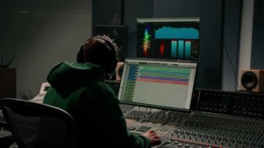 Stüdyo kayıt stüdyosunda çalışan enerji dolu ses mühendisi yapımcısı konsol ve hit yazılımları karıştırıyor.