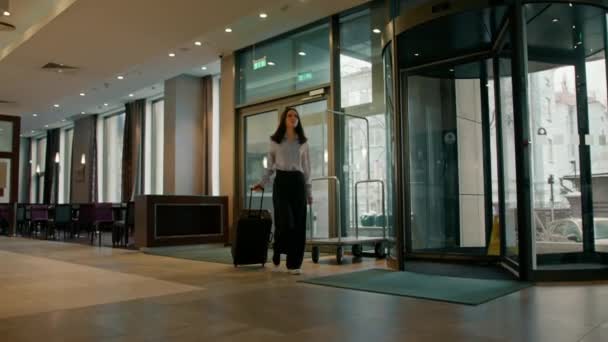 若いビジネスマンの女性がビジネスミーティングのためのスーツケースを持ってホテルに到着しました旅行のコンセプト — ストック動画