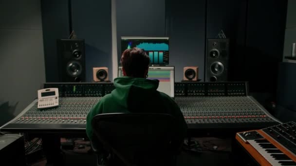 ヘッドフォン録音スタジオに置くサウンドプロデューサーのリアビューコンソールスピーカーとモニターを混合 — ストック動画