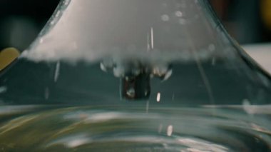 Baloncuklu duman, nargile şişesinde sudan geçiyor. Salonda bir masanın üzerinde duruyor.