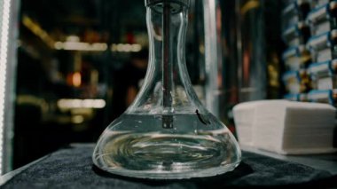 Baloncuklu duman, nargile şişesinde sudan geçiyor. Salonda bir masanın üzerinde duruyor.