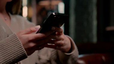 Genç kız elinde çay ve telefonla nargile barında oturup biriyle mesajlaşırken dinlenme konseptini kapatıyor.