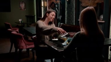 İki genç kız arkadaş bir nargile barında rahatça oturup eğlence kavramını tartışırlar.