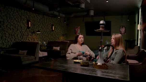 2人の若い女性の友人は フックバーでリラックスして座っています喫煙フカと楽しいチャットレクリエーションの概念を持って — ストック動画