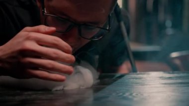 Nargilede nargile içen genç adam sigara ve rahatlama konseptine kalın beyaz duman üfledi.