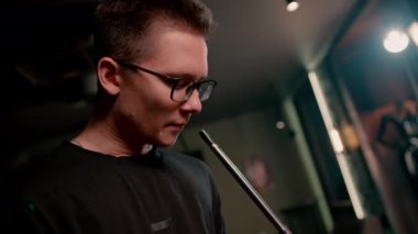 Gözlüklü bir adam geleneksel nargile piposu tüttürür. Bir adam nargile kafesinde ya da dinlenme odasında kalın dumanlı yüzükler solur.