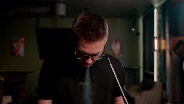 戴眼镜的男人抽传统的烟斗男人在烟斗咖啡店或酒吧间里喷出浓烟圈 — 图库视频影像