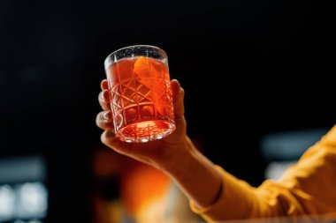 Elinde hazır nefis Negroni alkollü kokteyli tutan bir bar konuğunun yakın çekimi.