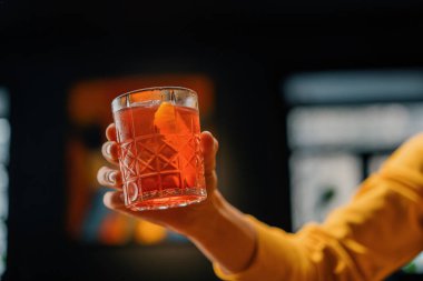 Elinde hazır nefis Negroni alkollü kokteyli tutan bir bar konuğunun yakın çekimi.