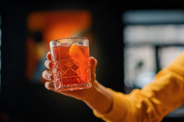 Elinde hazır nefis Negroni alkollü kokteyli tutan bir bar konuğunun yakın çekimi.