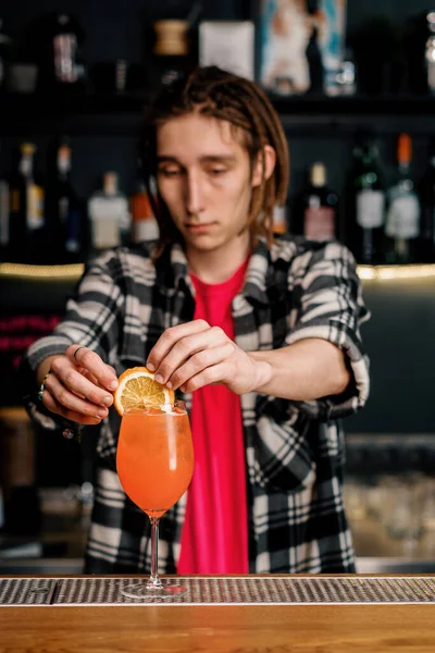 バーテンダーガーニッシュ氷とアルコールバーでいっぱいのワイングラスにオレンジのスライスを追加することでアペロールスプリッツカクテル — ストック写真