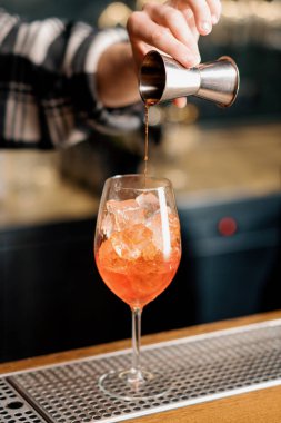 Hazırlık Aperol Spritz kokteyl barmeni bardaki buzlu bardağa içki dolduruyor.