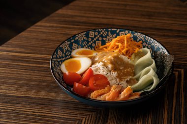 Doğu restoranında sosla kaplanmış sebzeli somon ve pirinçli lezzetli bir kase sağlıklı Asya yemeği.