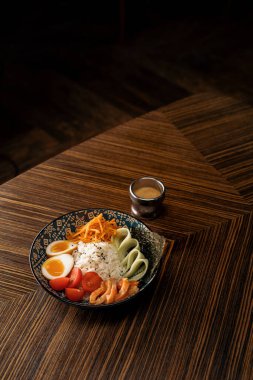 Doğu restoranında sosla kaplanmış sebzeli somon ve pirinçli lezzetli bir kase sağlıklı Asya yemeği.