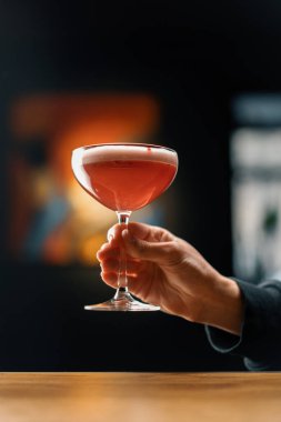 Müşteri elinde lezzetli pembe taze ahududu sütlü punç kokteyli tutuyor.