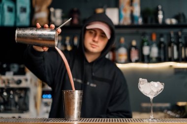 Kokteyl hazırlayan profesyonel barmen deneyimli barmen karıştırıcıya alkollü bir içecek koyar.